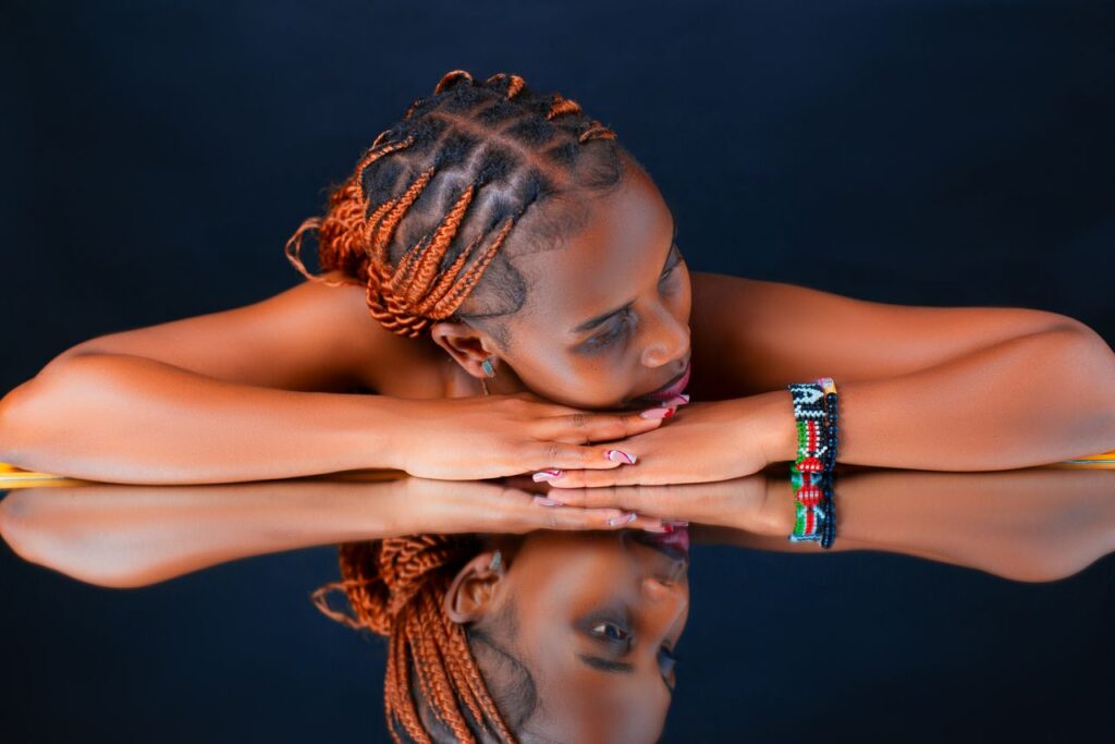 Elegant portrait of a woman with creative braided hairstyle reflecting on a shiny surface.